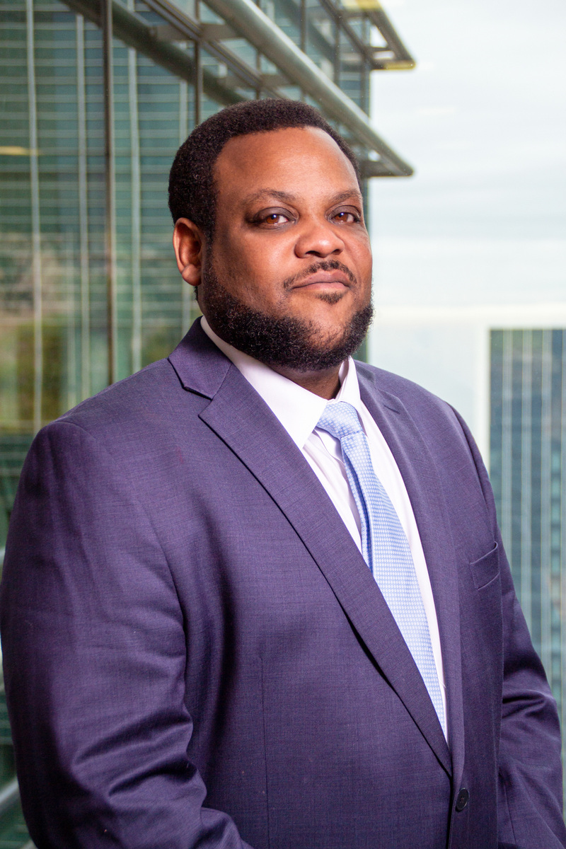 Confident male corporate executive in a blue suit standing in front of a modern office building